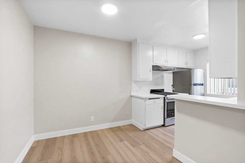 a kitchen with white cabinets and white appliances and a wood floor
