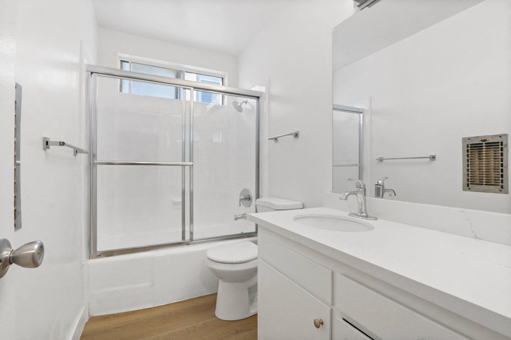 a white bathroom with a shower toilet and sink