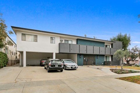 A modern two-story house with a garage and two cars parked in front.