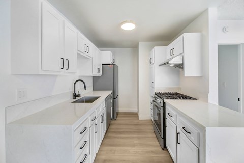 A kitchen with white cabinets and a marble countertop.