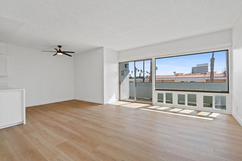 A room with a ceiling fan and a large window overlooking a cityscape.