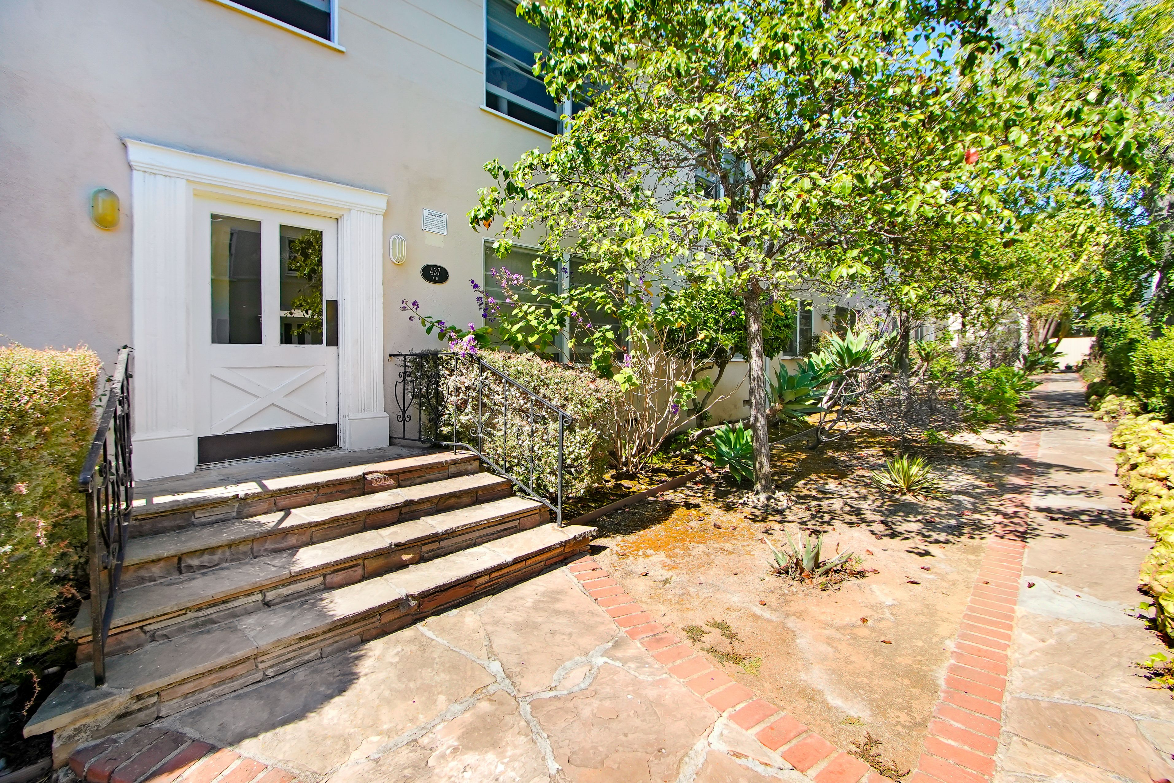 A house with a white door and a small garden in front.