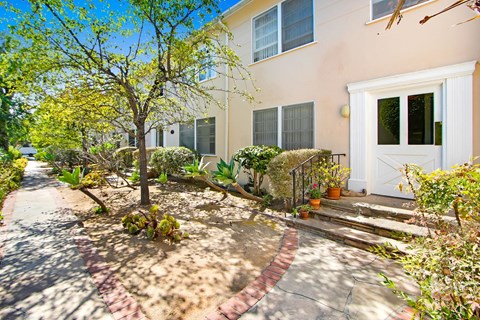 A house with a white door and a tree in front of it.