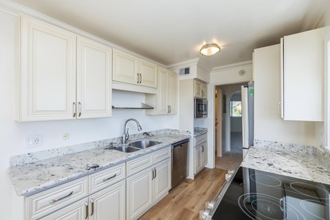 A kitchen with white cabinets and granite countertops.
