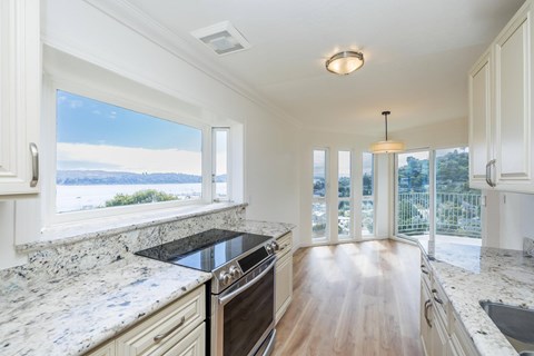 A kitchen with a marble countertop and a view of the outdoors through the windows.