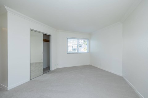 A large empty room with a window and a door.