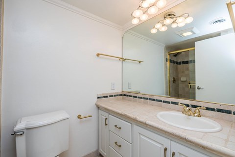 A white bathroom with a sink, toilet, and a mirror.
