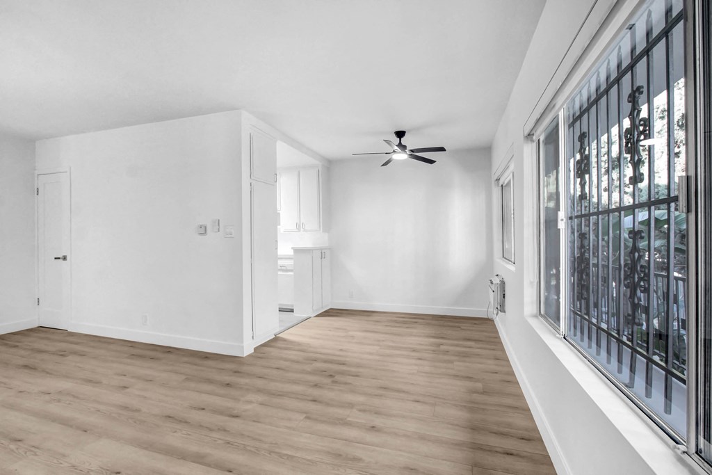 a living room with white walls and a large window and a ceiling fan