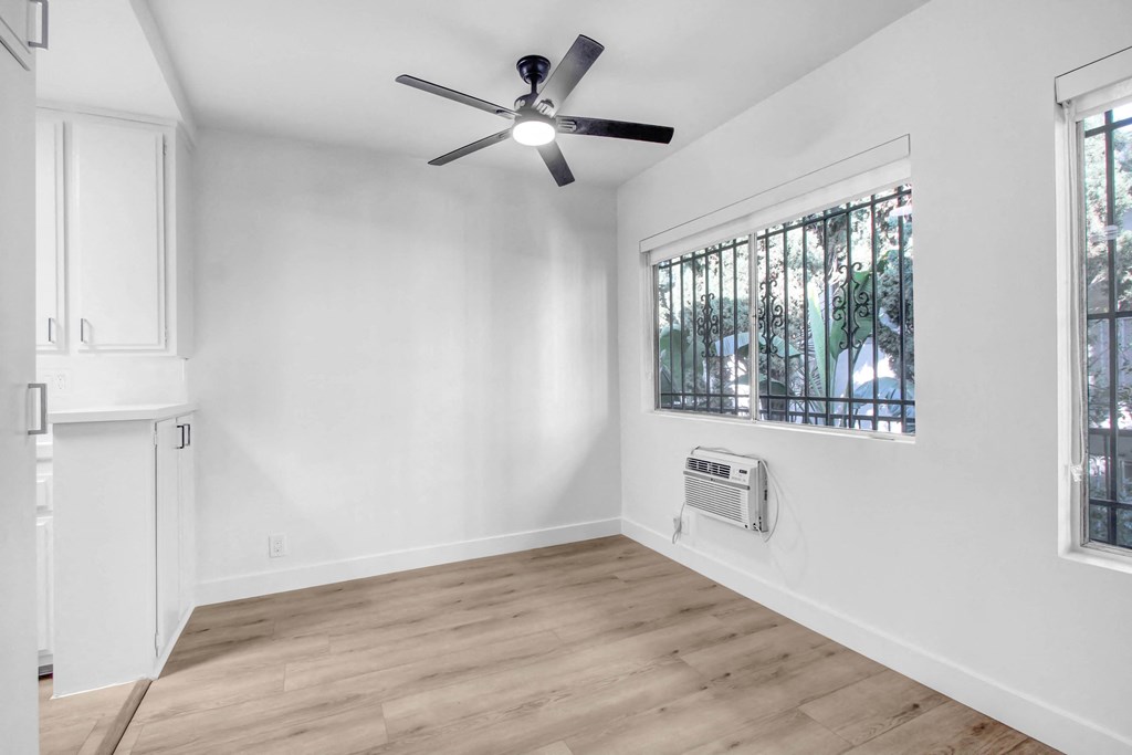 an empty living room with white walls and a ceiling fan