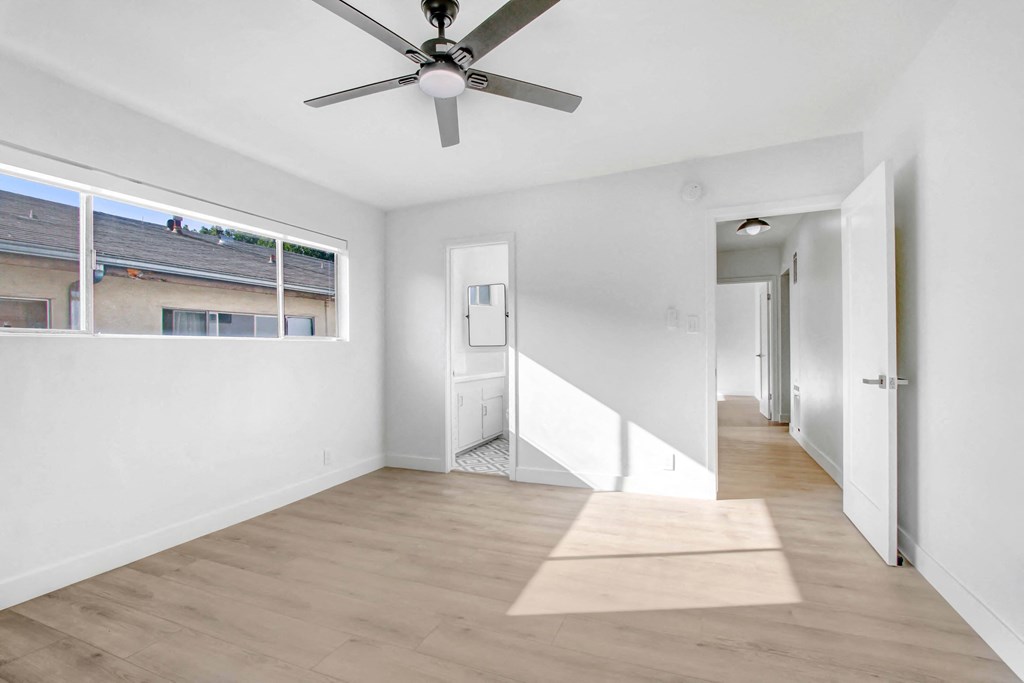 a living room with white walls and a ceiling fan