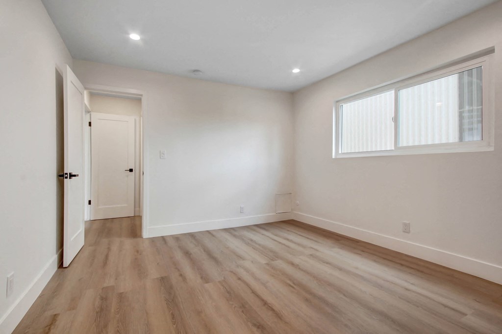 an empty living room with white walls and wood floors