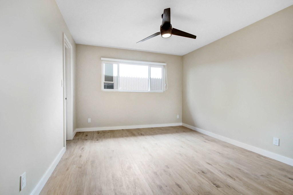an empty room with wood floors and a ceiling fan