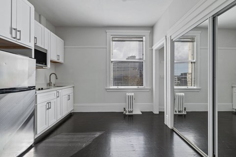 A kitchen with white cabinets and a black floor.