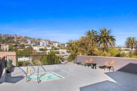 A pool area with chairs and a view of a city in the background.