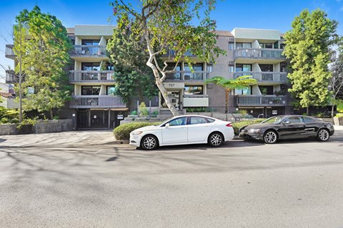 Two cars parked in front of apartment buildings.