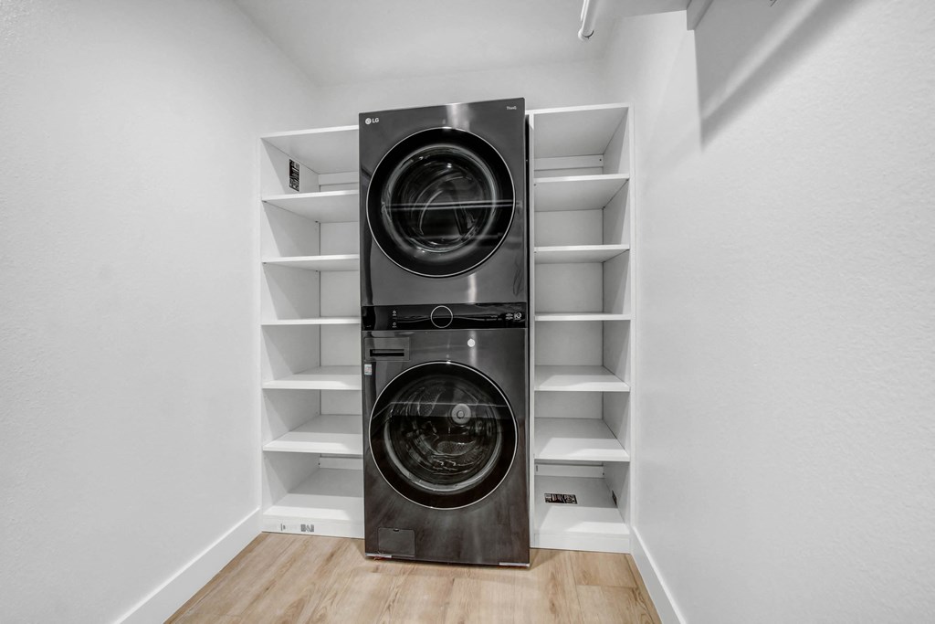 a front loading washer and dryer in a laundry room with white shelves