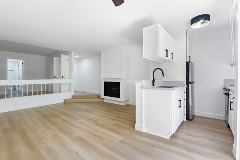 A kitchen with white cabinets and a wooden floor.