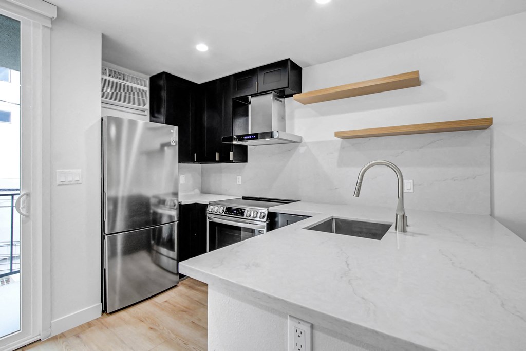 a white kitchen with black cabinets and a stainless steel refrigerator
