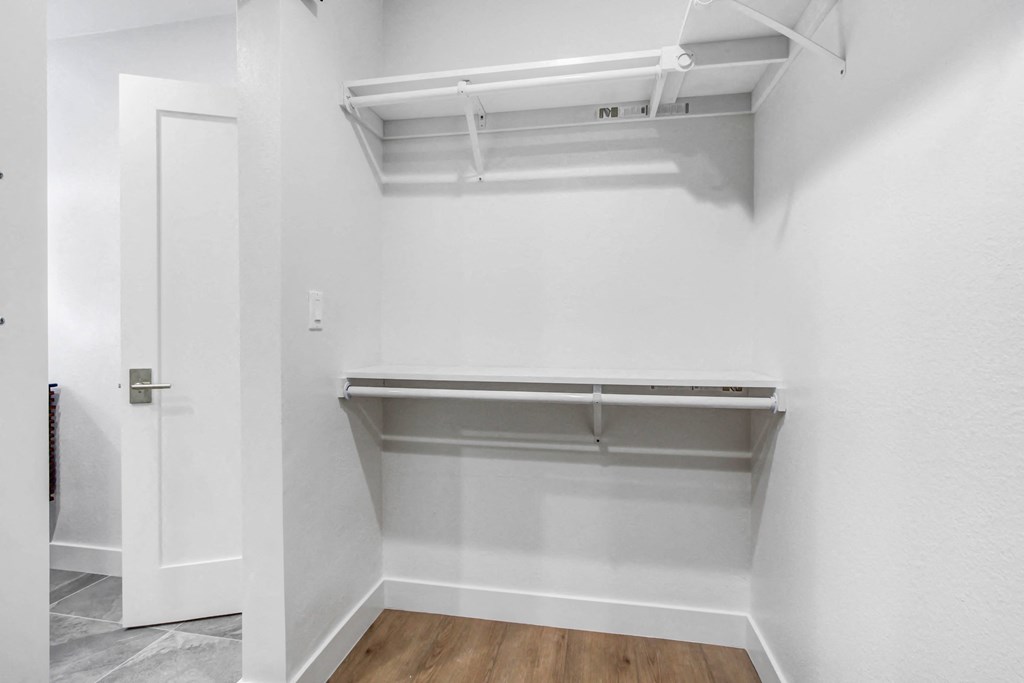 a empty closet with white walls and a wood floor
