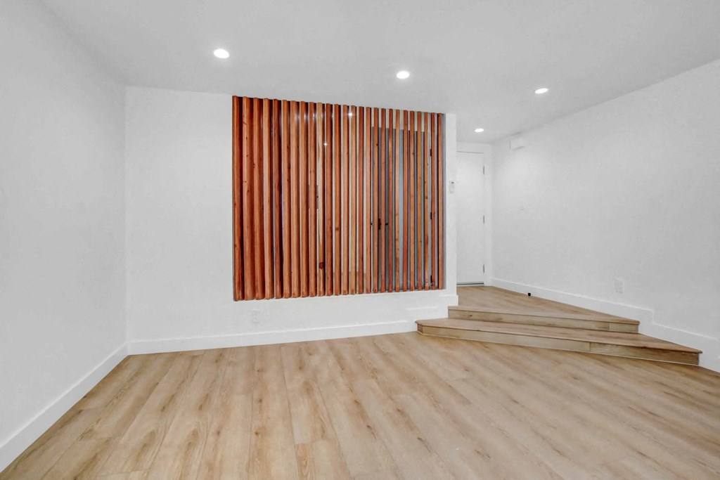 a room with wood floors and a wall with a staircase