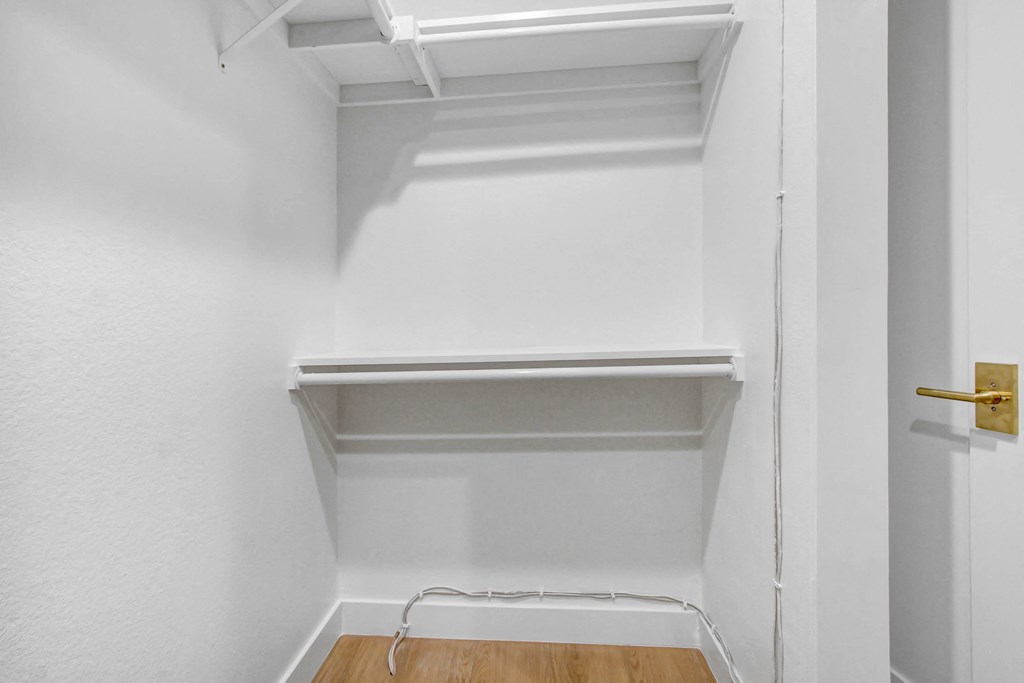 an empty closet with a wooden floor and white walls