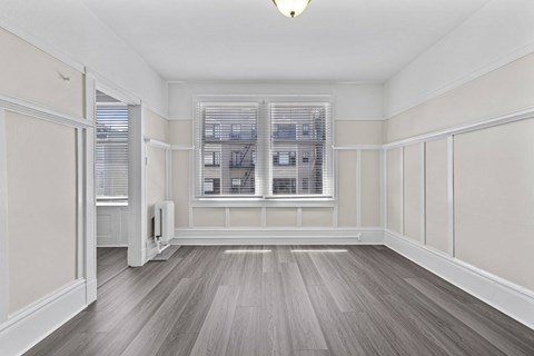 A room with a window and a wooden floor.