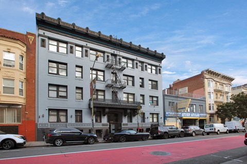 A street view of a city with cars parked on the side of the road and buildings in the background.