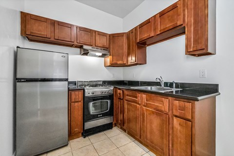 A kitchen with a stainless steel refrigerator and wooden cabinets.