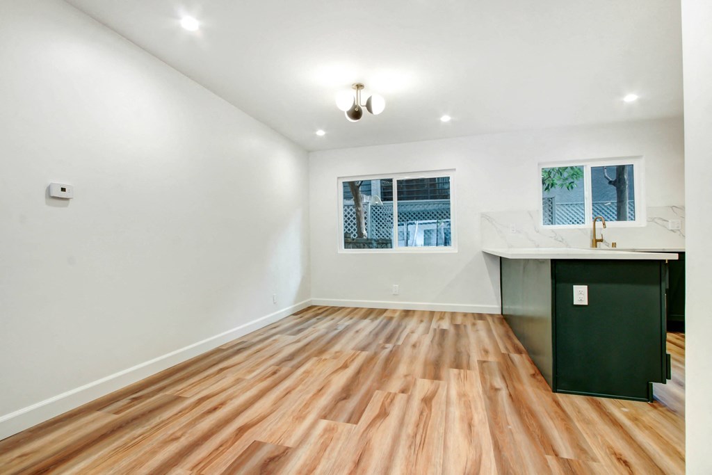 a living room with hardwood floors and a kitchen with a counter and a window