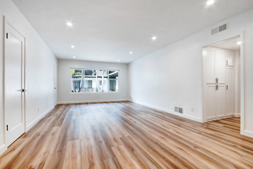 an empty living room with white walls and wood floors