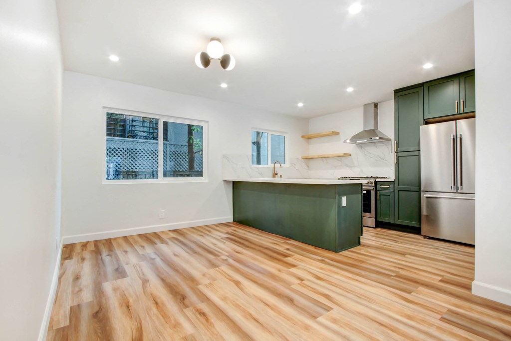 a renovated kitchen with green cabinets and a wooden floor