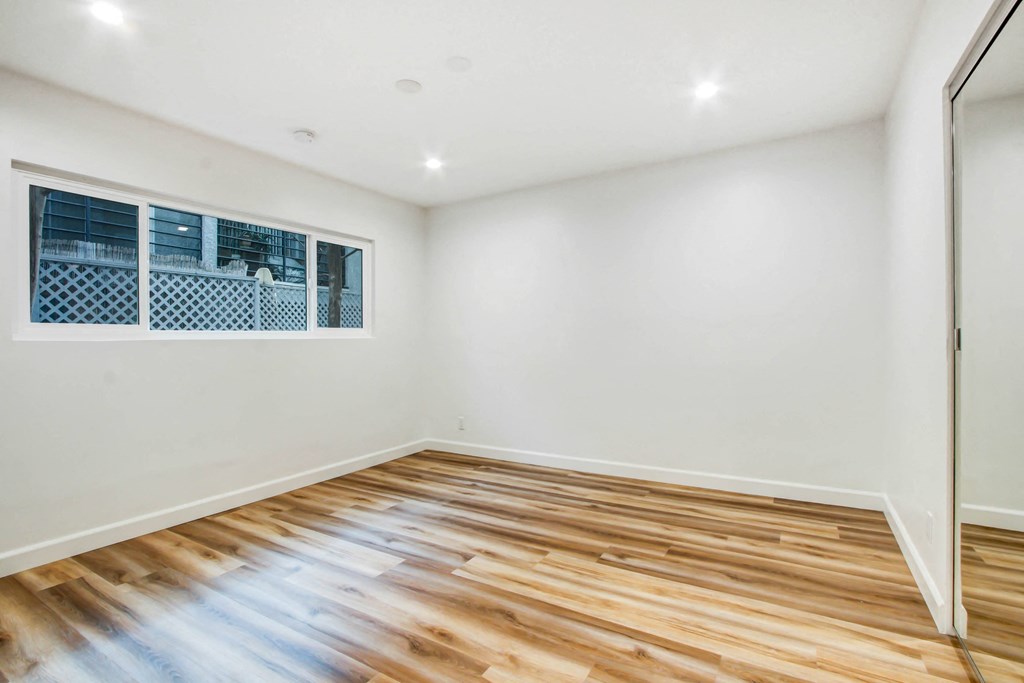 an empty living room with wood flooring and a window