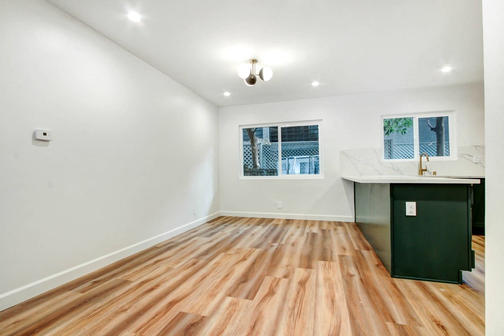 a living room with hardwood floors and a kitchen with a counter and a window