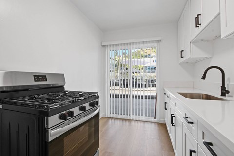 A kitchen with a black stove top oven and white cabinets.