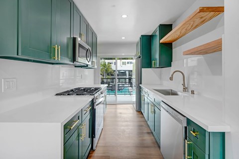 A kitchen with green cabinets and white countertops.