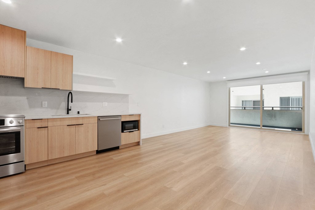 a living room and kitchen with wooden floors and wooden cabinets