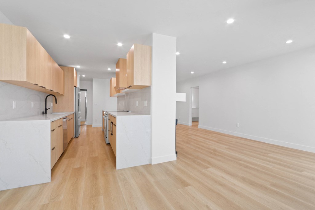 a kitchen and living room with wood flooring and white counter tops and