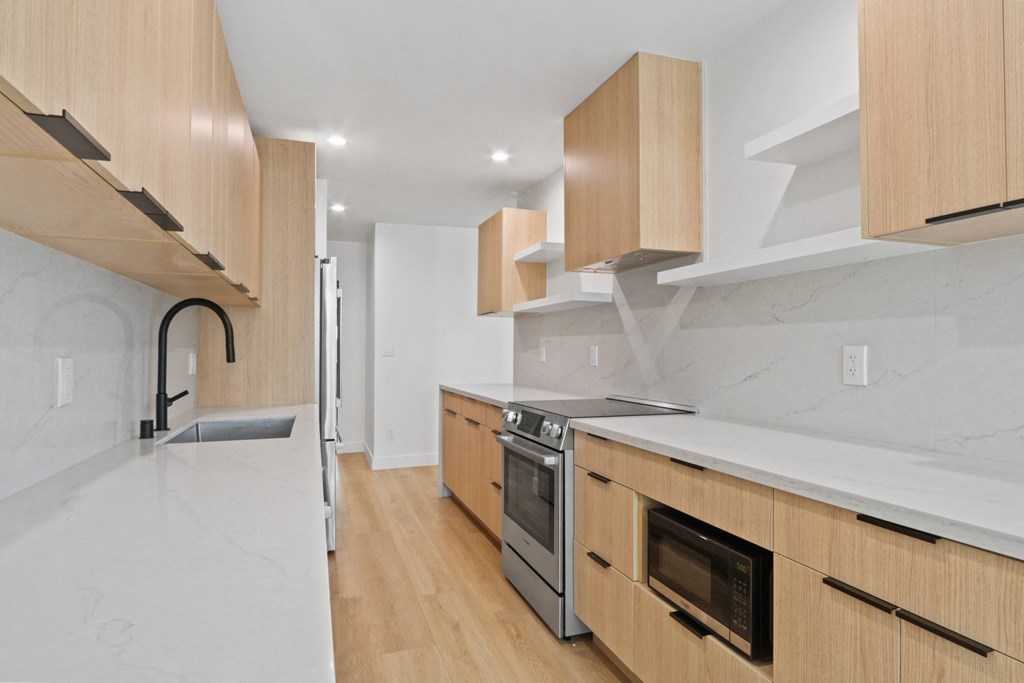a kitchen with wooden cabinetry and marble counter tops and a sink