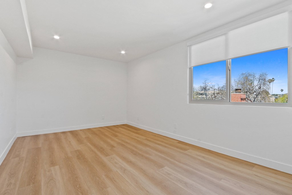 a living room with white walls and wooden floors and a window