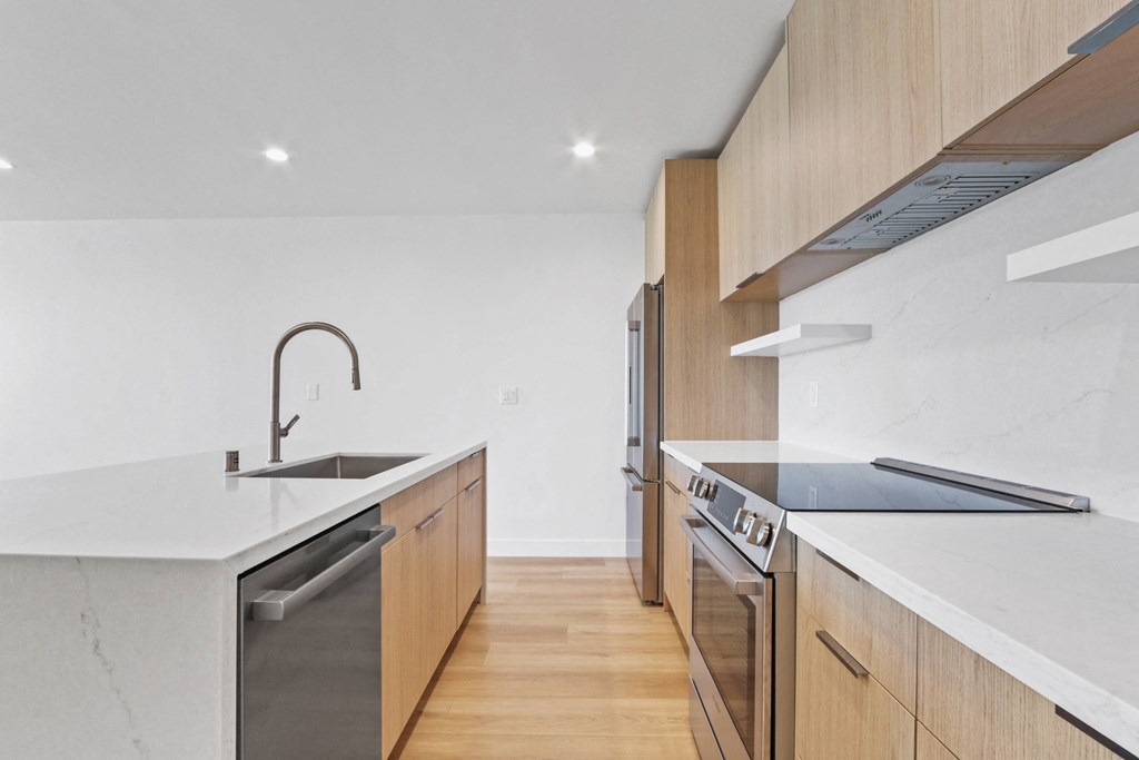 a kitchen with wooden cabinetry and white counter tops and a sink
