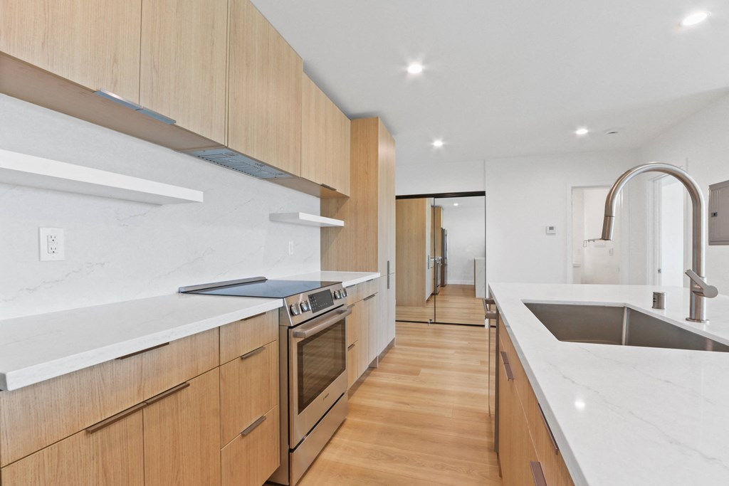 a kitchen with wooden cabinetry and white counter tops and a sink