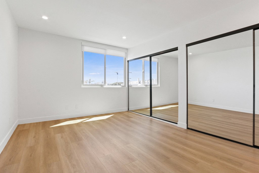 a living room with white walls and wood flooring and sliding glass doors
