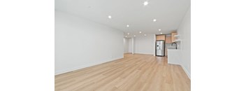 A spacious room with wooden flooring and a kitchenette in the corner.