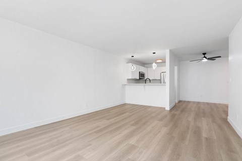A room with a ceiling fan and a countertop with a microwave.