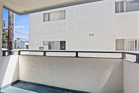 A white building with a balcony and a blue pool.