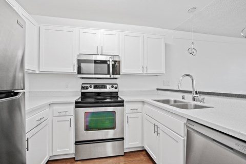 A modern kitchen with white cabinets and stainless steel appliances.
