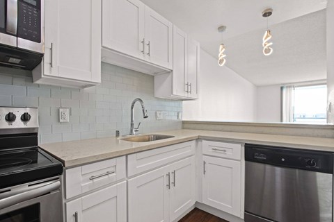 A kitchen with white cabinets and a black oven.