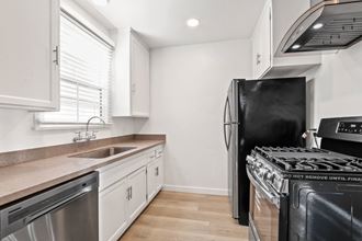 a kitchen with white cabinets and stainless steel appliances and a black stove and refrigerator