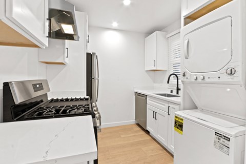 A white kitchen with a black stove top and a white oven.