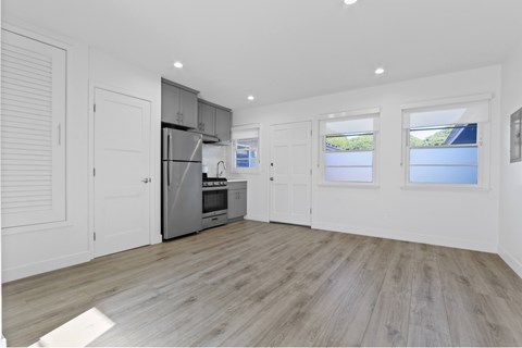 A spacious kitchen with wooden flooring and white walls.